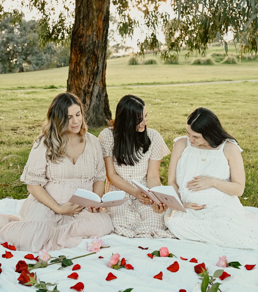 a group of women sitting on a blanket in a park